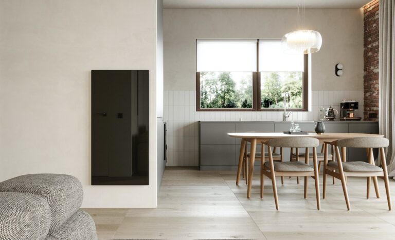 A minimalist open plan kitchen and dining space with black infrared panel heating on the wall.