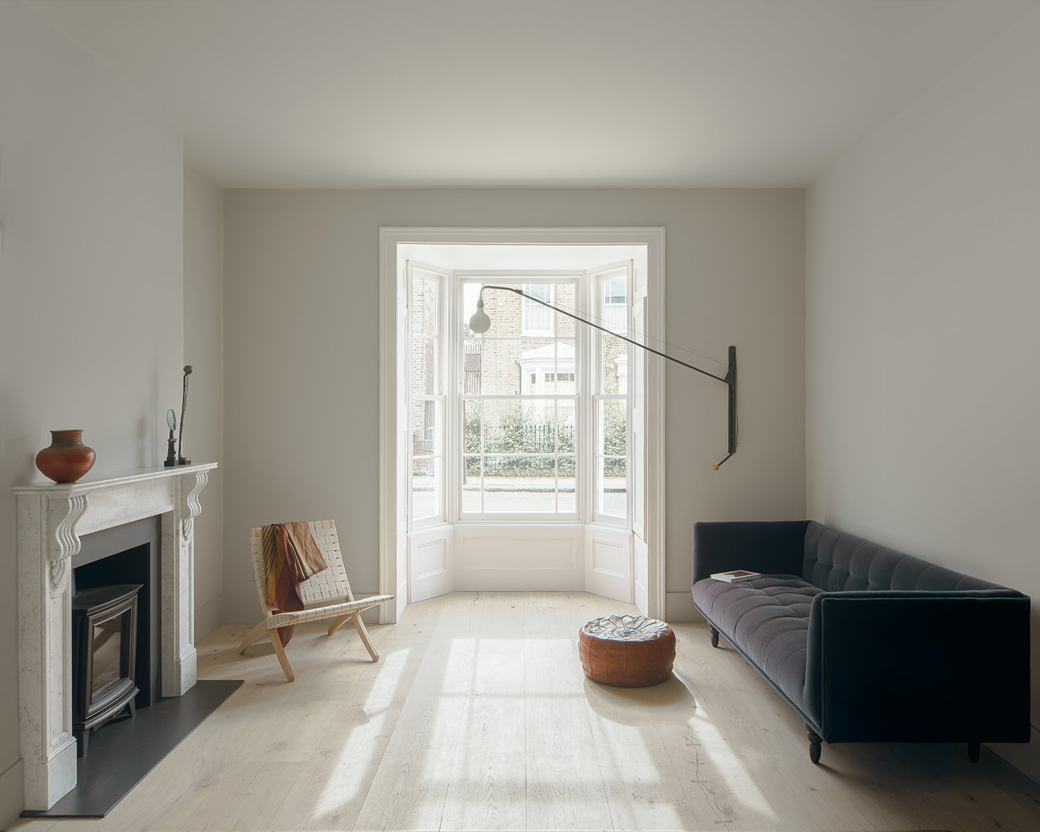 Light modern front room of Victorian house with bay window and marble fireplace