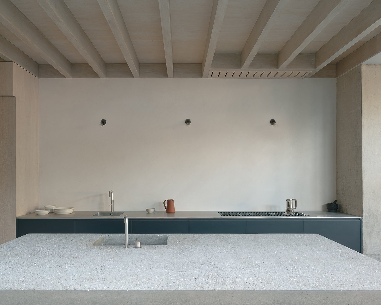 Concrete kitchen island in modern kitchen with light wood beamed ceiling