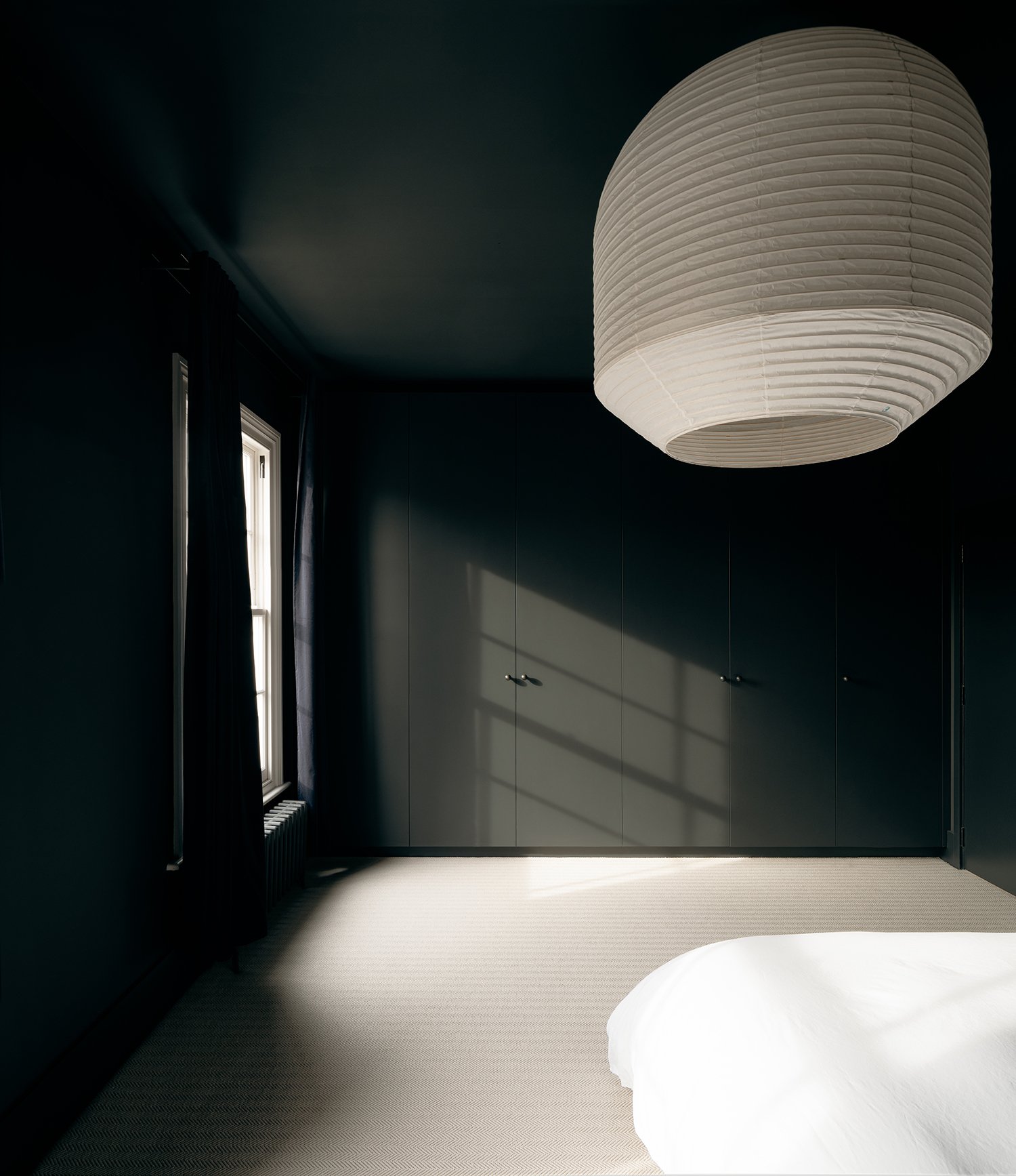 dark black bedroom with large white paper lantern light