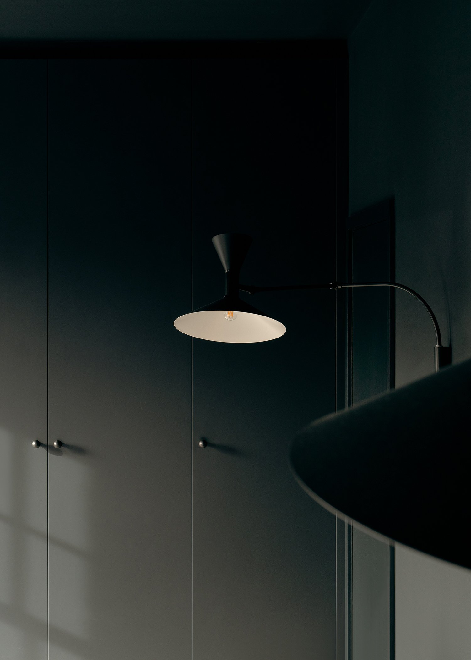 Bedside lamp and built in wardrobes in dark black bedroom