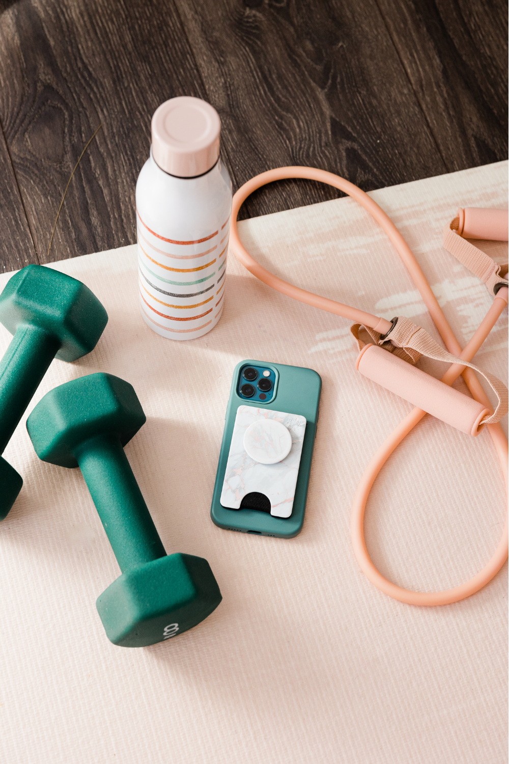 Home gym equipment - a dumbell, skipping rope and water bottle on a yoga mat.
