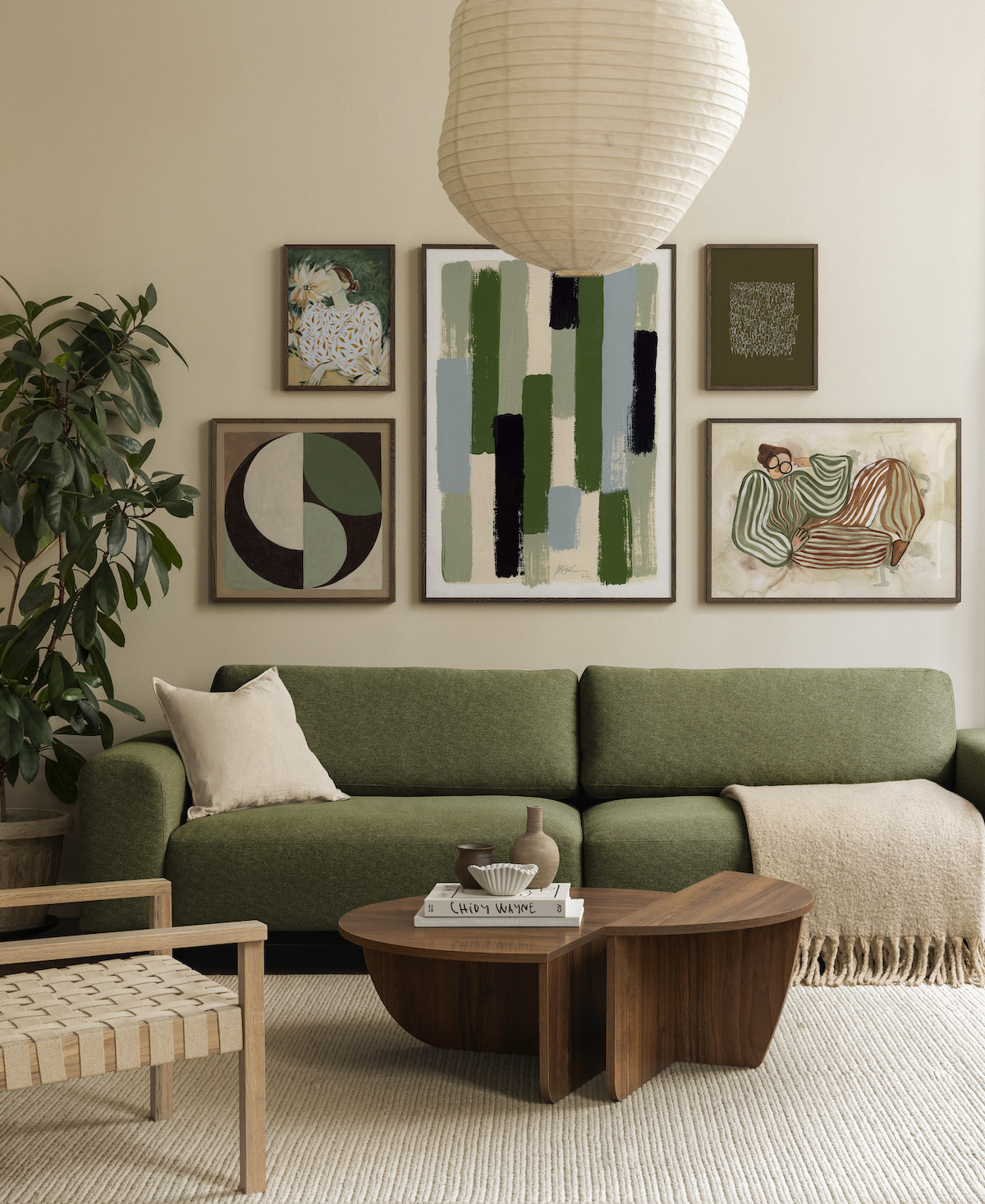 A modern living room with a green sofa, abstract green-themed gallery wall, wooden furniture, and neutral decor elements.