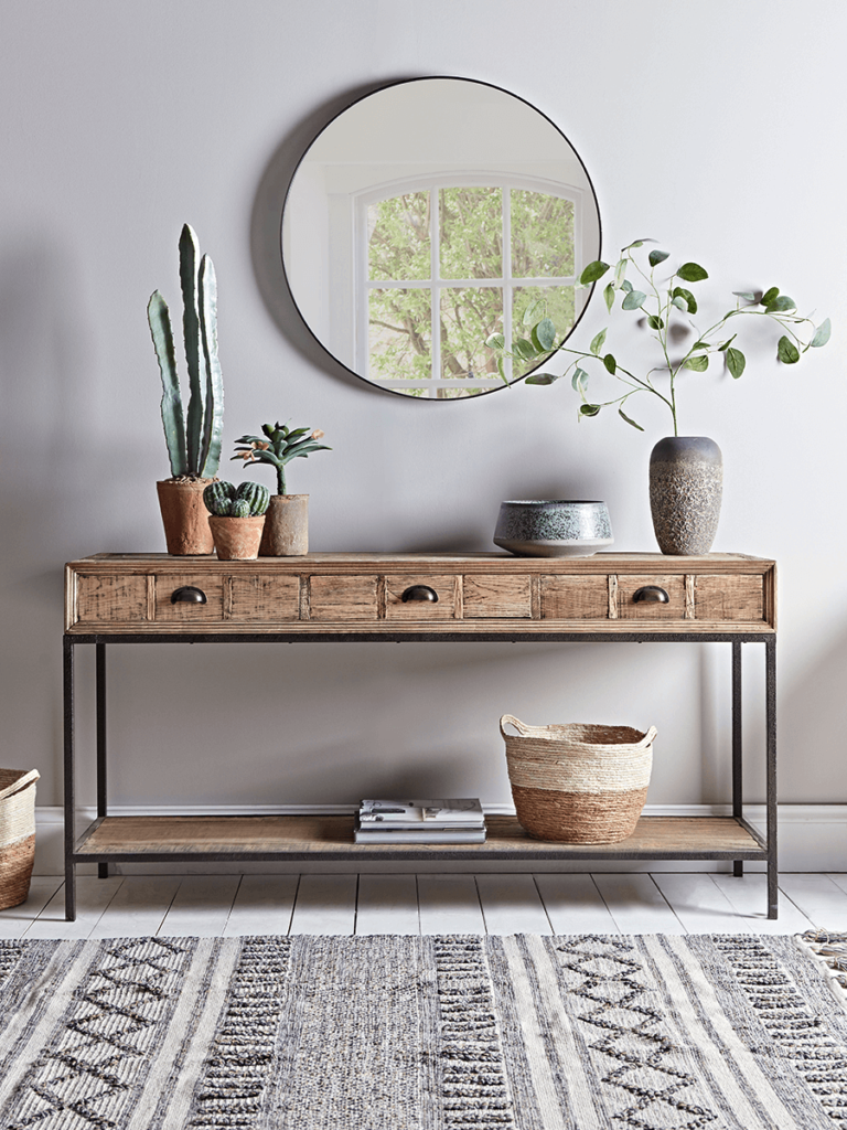 A trio of terracotta plant pots containing cacti arranged on a reclaimed wood console table.