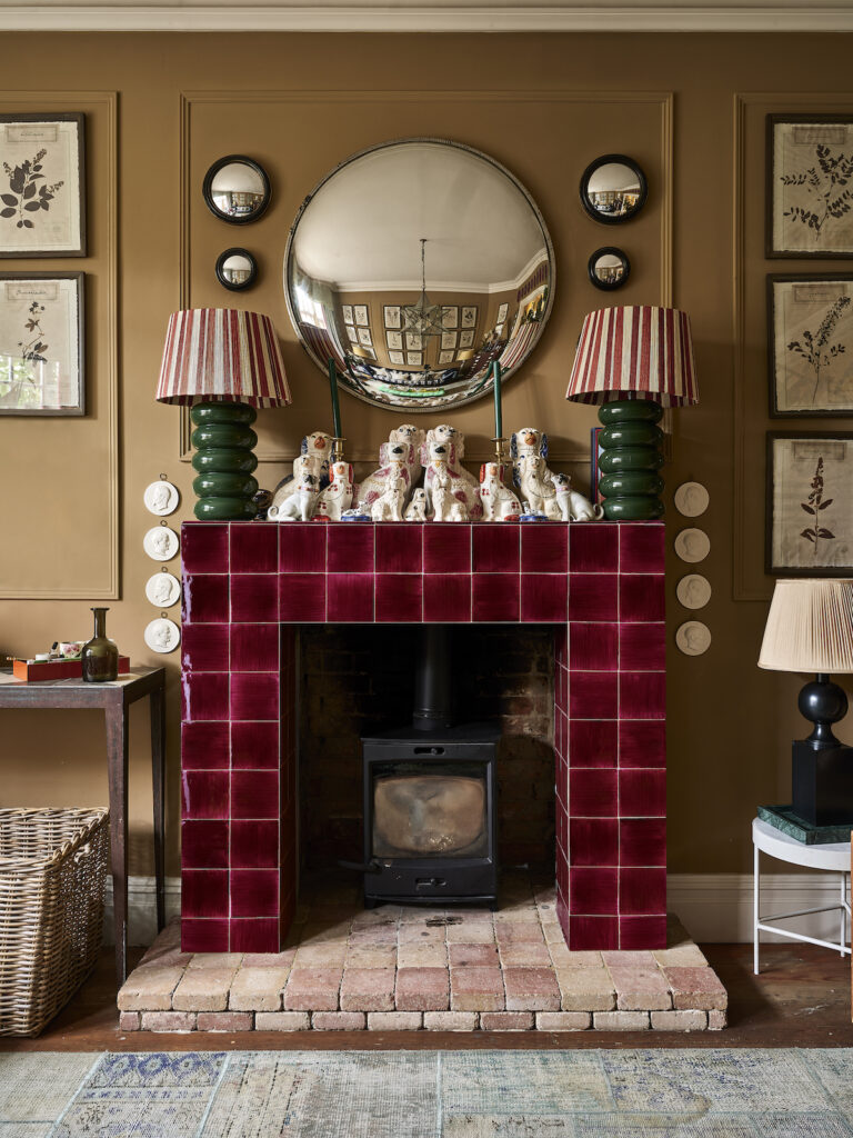 A striking cherry-red tiled fireplace set against warm neutral walls, styled with vintage-inspired decor for a cozy yet sophisticated aesthetic.