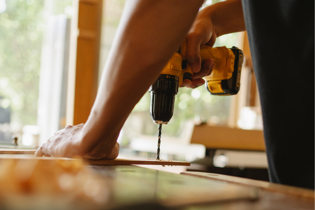 A person drilling a piece of wood.